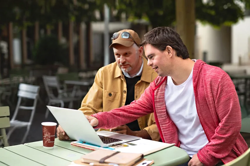 Bild 4 im Slider: Zwei Personen sitzen an einem Tisch und arbeiten zusammen.